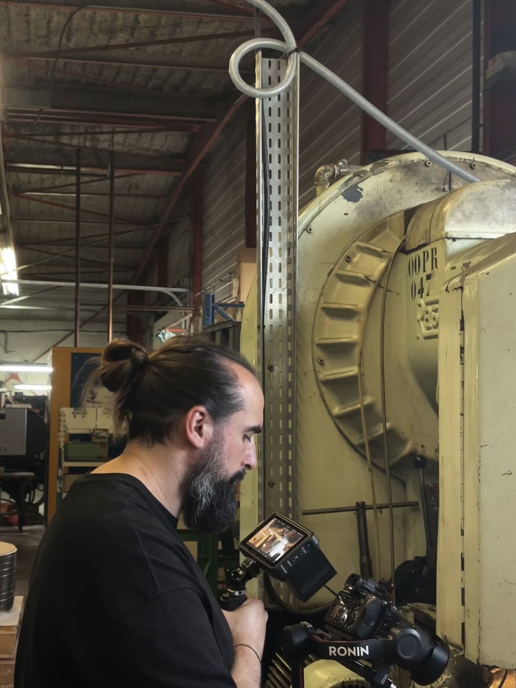 Yannick Vigne, vidéaste d'Engivy Production, en tournage dans un atelier industriel avec une caméra sur stabilisateur